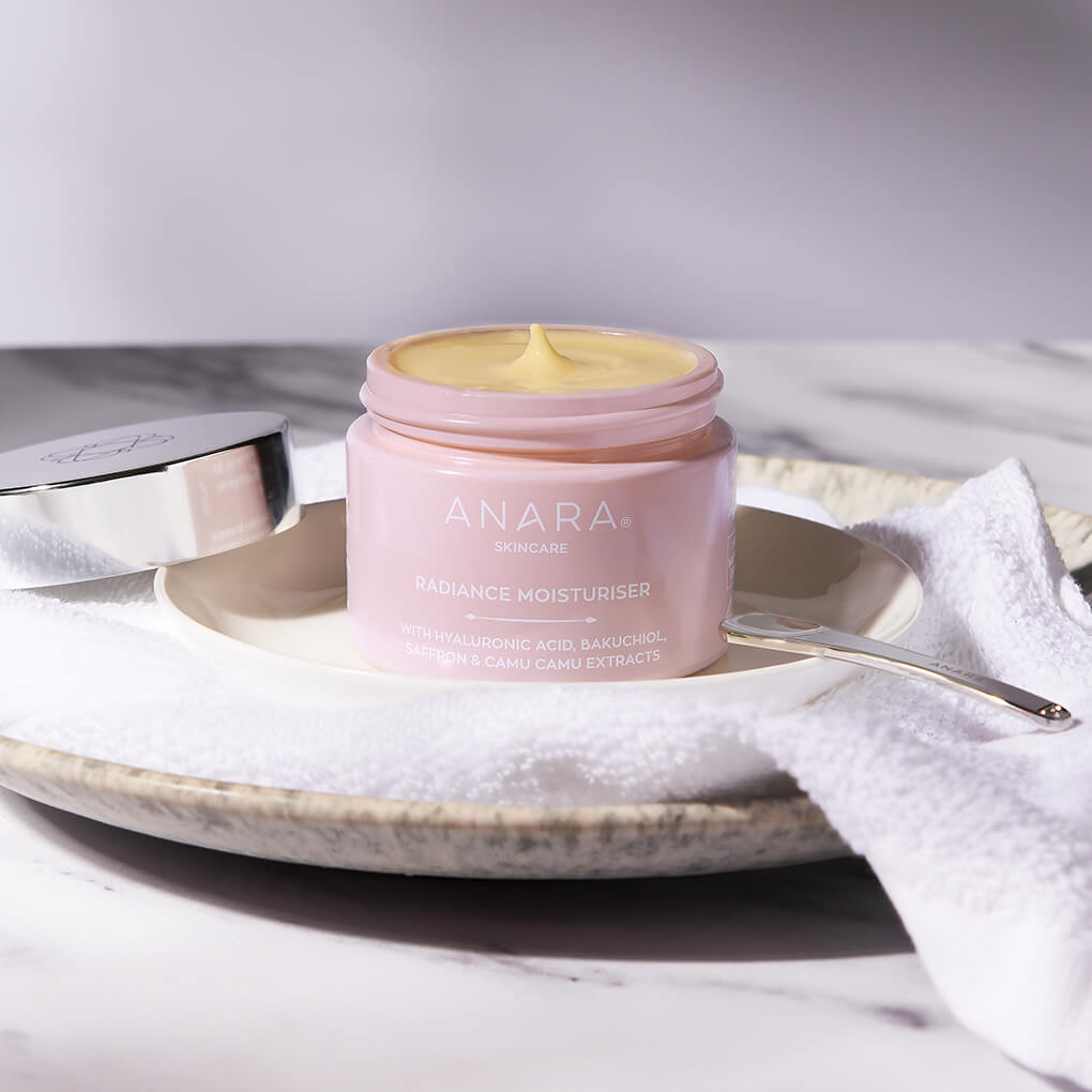 Anara Skincare Radiance Moisturiser in jar with lid off, with spatula, sitting on a face cloth