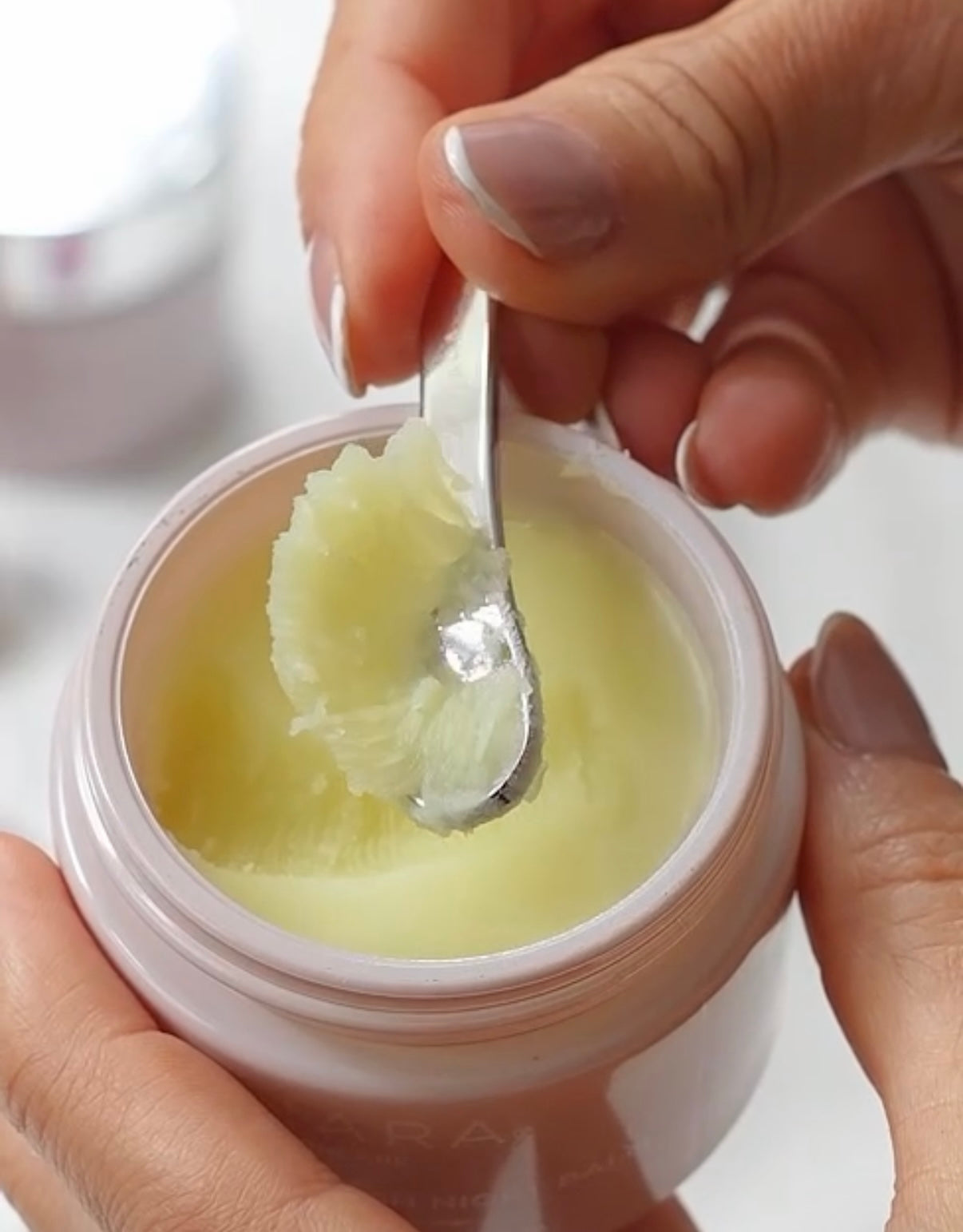 Hand holding a spatula with a scoop of Anara Cleanse & Nourish Night Balm