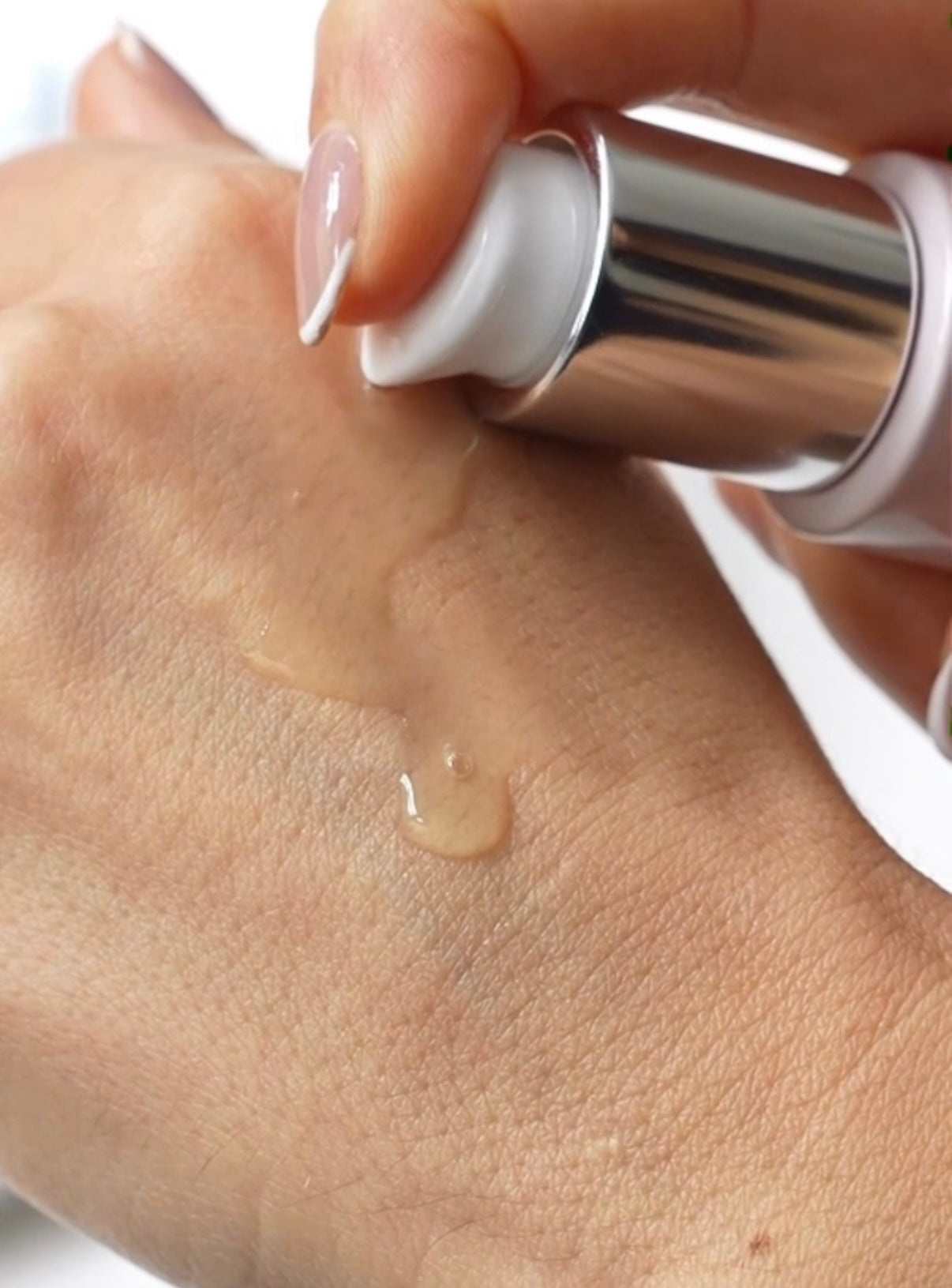 Hand dispensing a pump of Anara Hydrating Beauty Essence onto the hand to show the water light texture