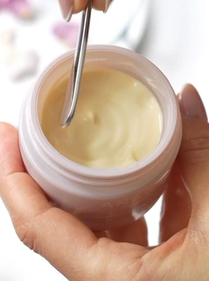 Hand holding a jar of Radiance Moisturiser with Anara spatula about to scoop