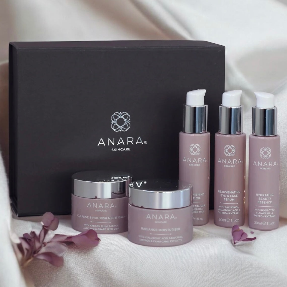 Anara Radiance Moisturiser, Rejuvenating Eye & Face Serum, Hydrating Beauty Essence, Cleanse & Nourish Night Balm and Replenishing Face Oil with grey magnetic gift box with Anara logo in silver in the background