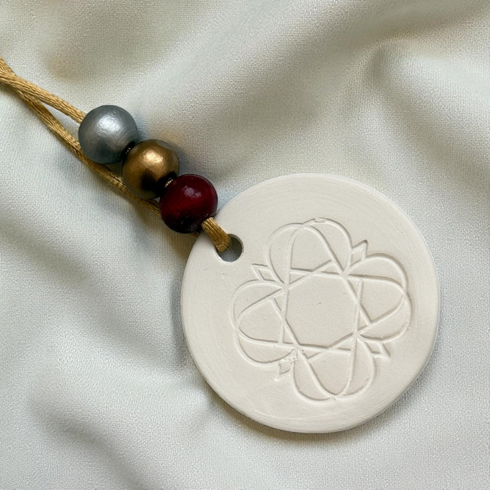 
                  
                    Anara emblem keepsake scent diffuser with beaded hanging on cream fabric
                  
                