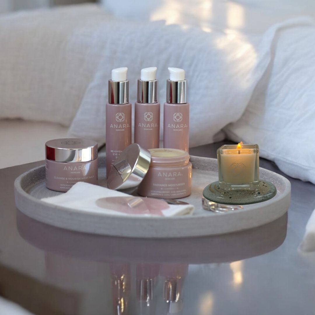 Anara Skincare range on a grey tray with Anara candle in a bedroom