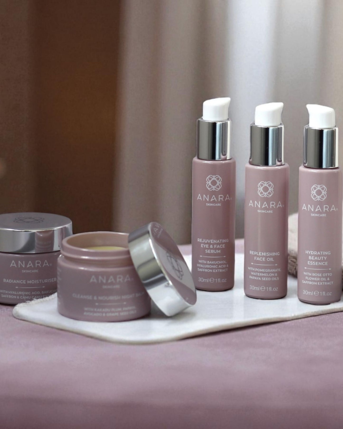 Anara skincare products including jars and bottles on a marble surface with a neutral background.