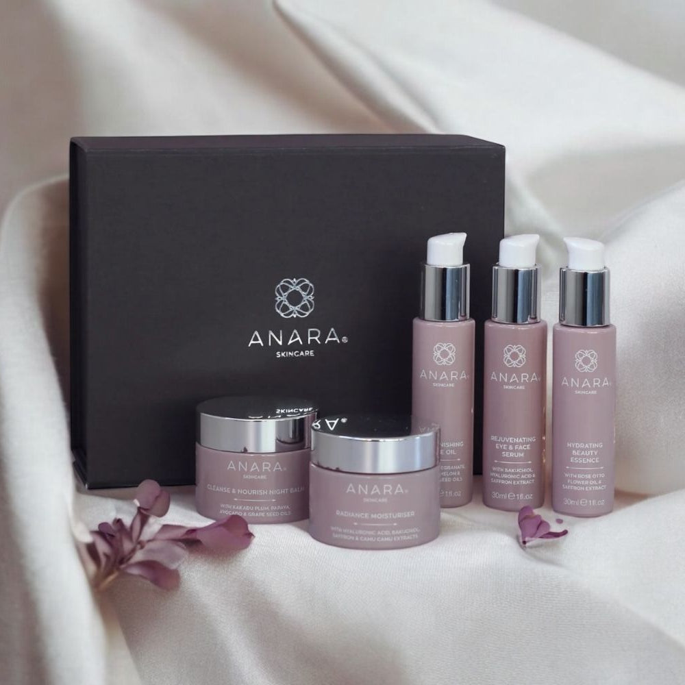 Anara skincare products including bottles and jars on a cream fabric with a grey gift box in the background.