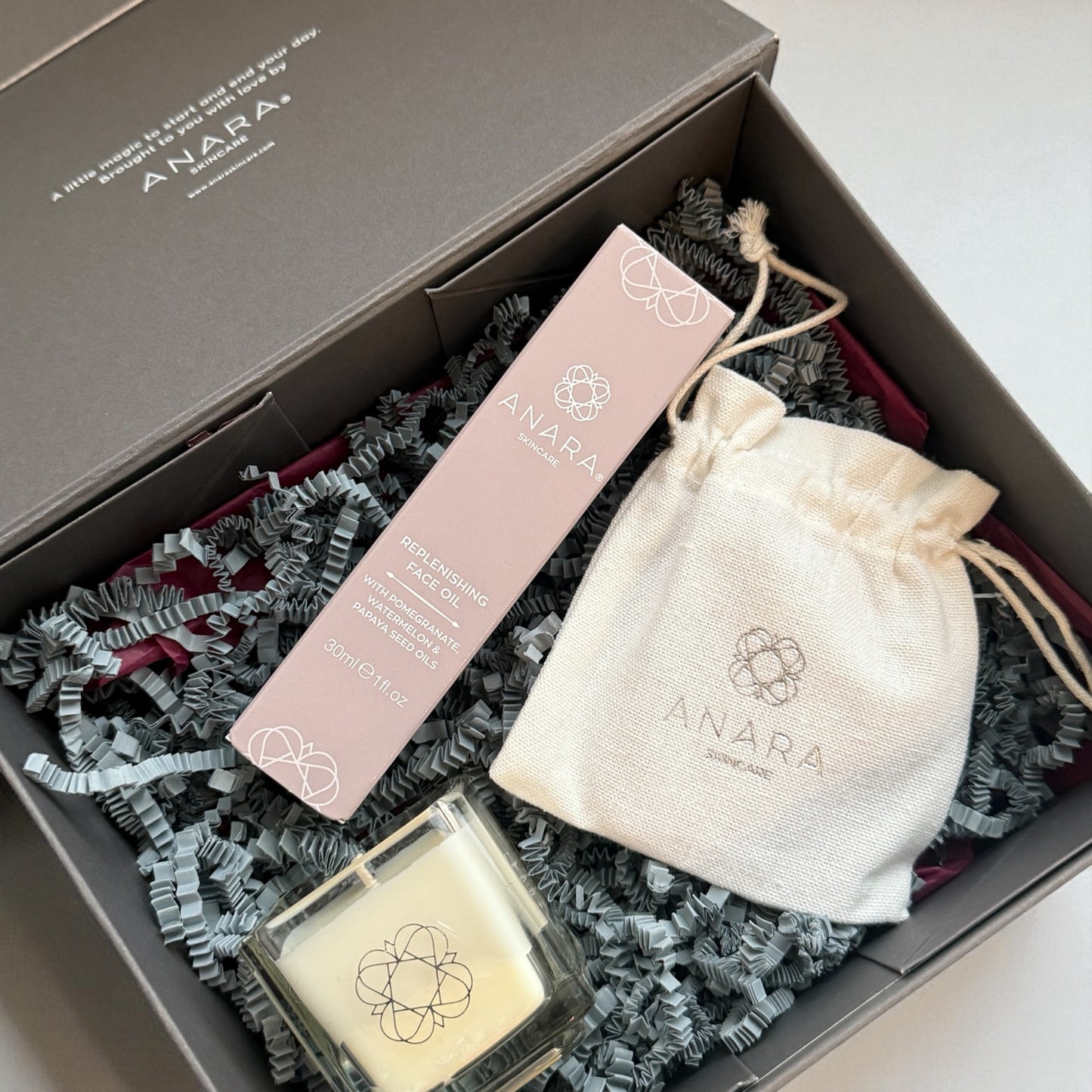 Anara Your Moment Candle, Replenishing Face Oil in carton and Rose Quartz Gua Sha pouch in gift box