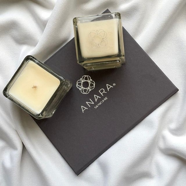 Two Anara Skincare square candles on top of gift box
