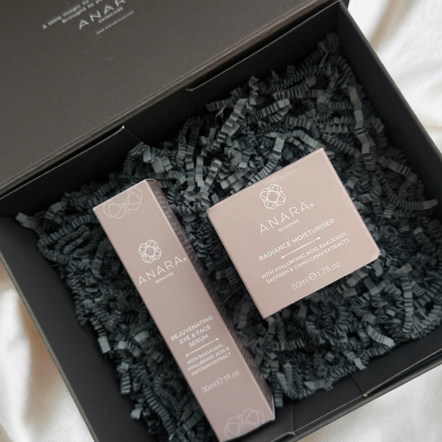 Anara Rejuvenating Eye & Face Serum and Radiance Moisturiser in their outer cartons presented in grey Anara branded magnetic gift box
