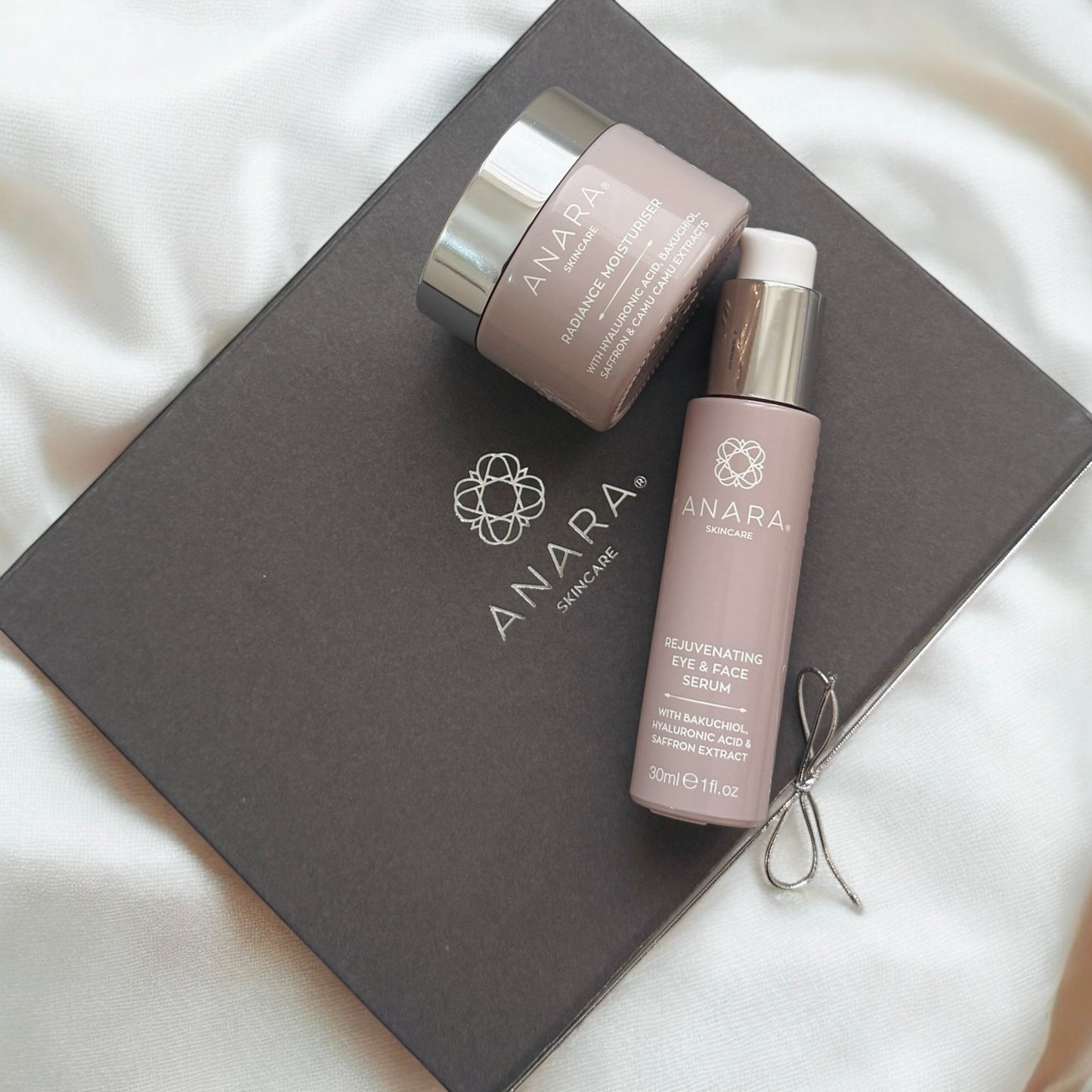Anara Radiance Moisturiser and Rejuvenating Eye & Face Serum on grey magnetic gift box with Anara logo in silver