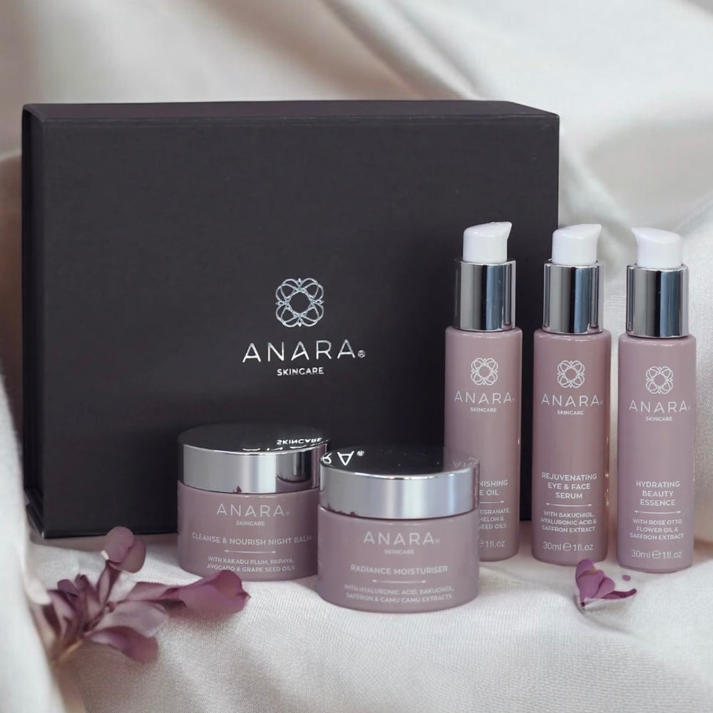 Anara Radiance Moisturiser, Rejuvenating Eye & Face Serum, Hydrating Beauty Essence, Cleanse & Nourish Night Balm and Replenishing Face Oil with grey magnetic gift box with Anara logo in silver in the background
