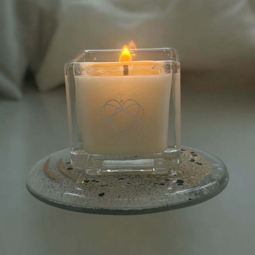 Anara cube candle being lit, standing on a fused glass plate